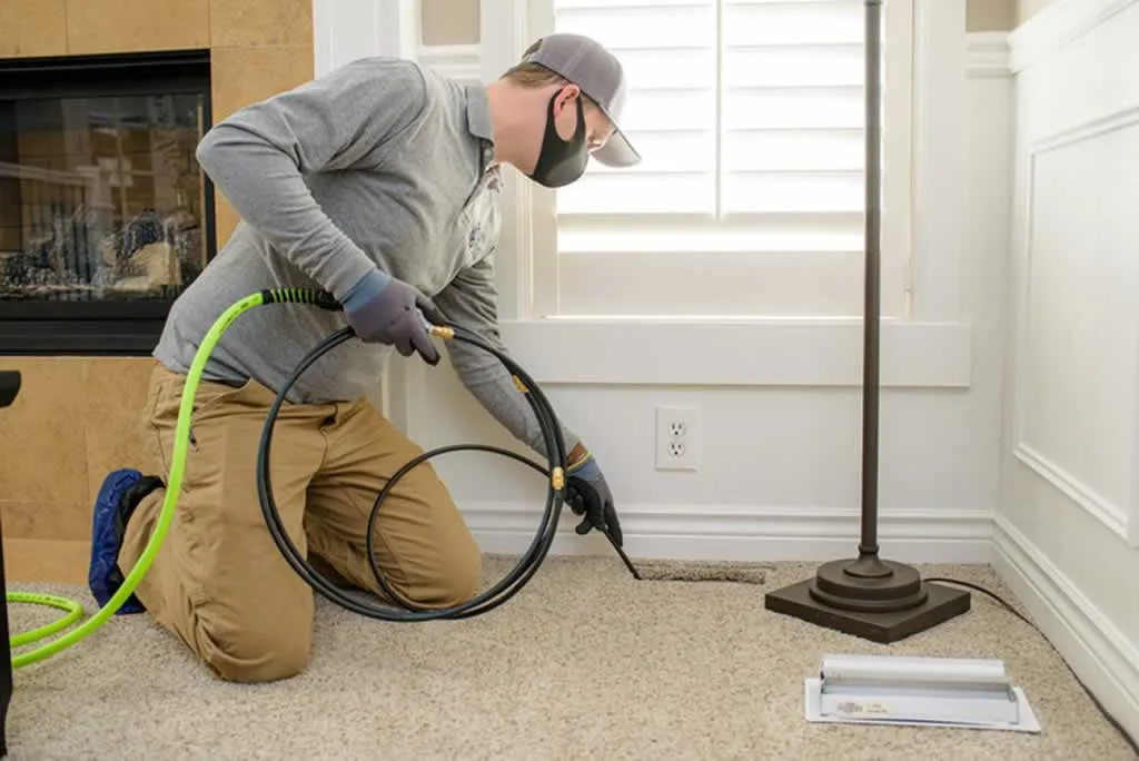 technician cleaning air duct in the floor
